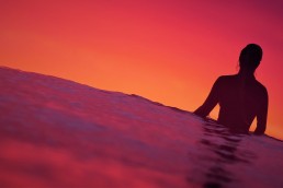 Surfer-Girl-waiting-for-a-wave-with-the-sun-setting-in-the-background